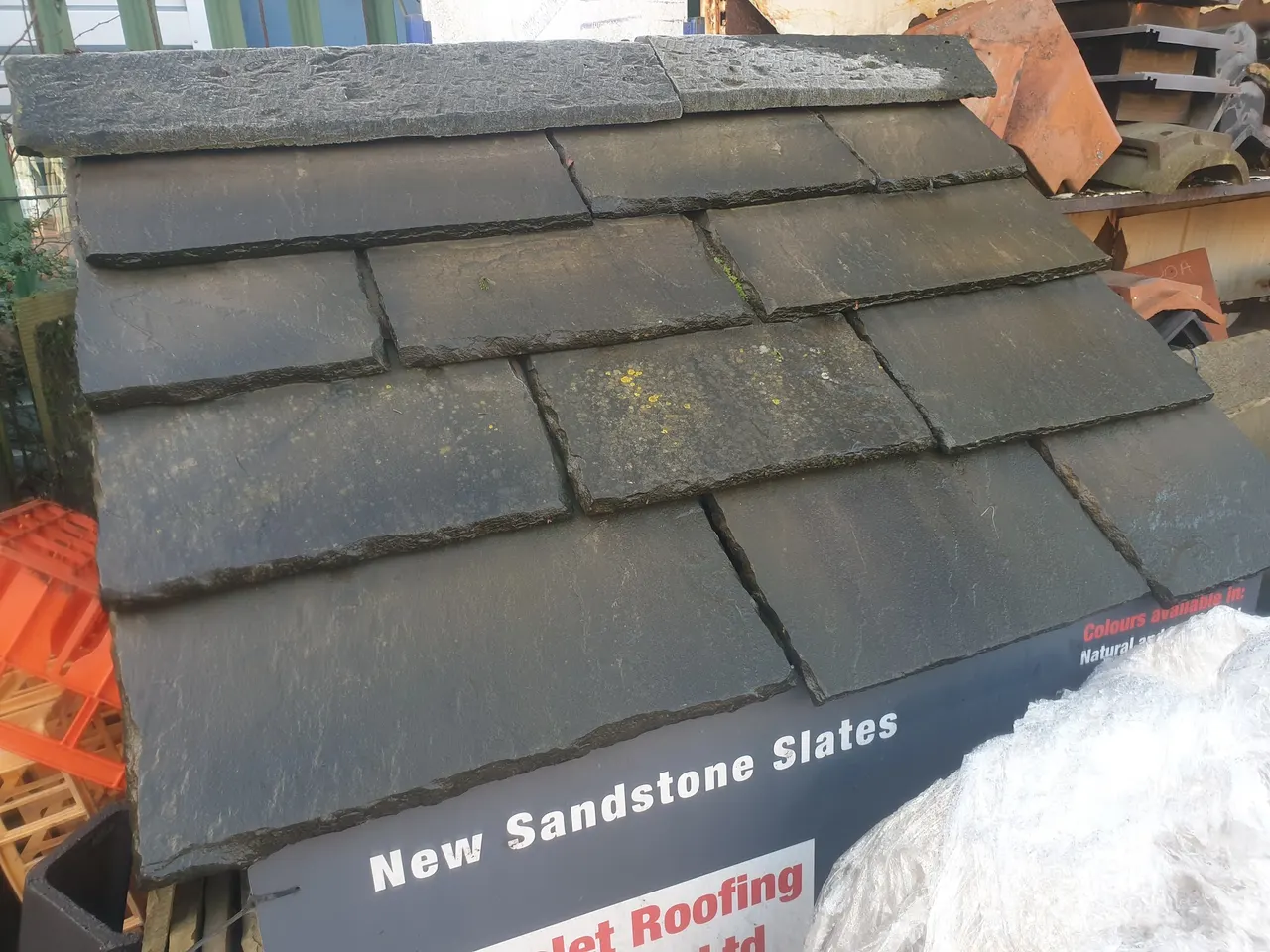 Sandstone roofing slates displayed with Hunslet Roofing Supplies signage